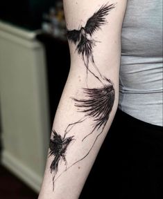 a woman's arm with two black birds flying in the sky on her left arm