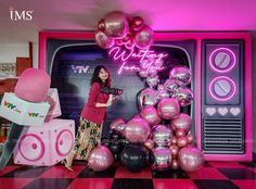 a woman standing in front of a display of pink and black balloons with the words whimfy fun on it