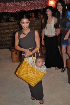 a woman holding a yellow purse standing next to two other women