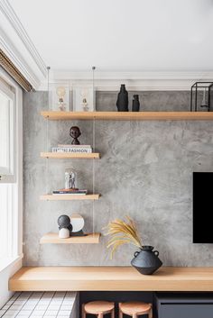 a tv mounted on a wall in a living room next to two wooden stools