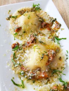 two ravioli with cheese and herbs on a white plate, ready to be eaten