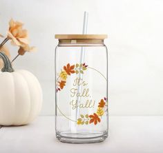 a glass jar with a straw in it next to a pumpkin