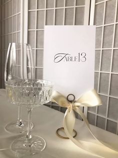 two wine glasses sitting on top of a table next to a card with the word able 3