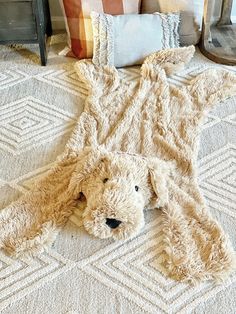 a teddy bear laying on the floor next to pillows