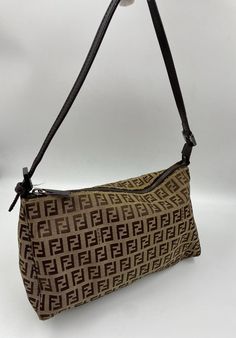 A stunning Fendi Pochette shoulder bag. Made in the classic Fendi beige/brown Zucca Canvas. Brown leather top handle and Fendi branded silver hardware. Inside there is an internal slip pocket for your valuables. This bag is in great condition with minor signs of wear. The hardware has slight scratches. The external canvas has one small stain (is pictured). Lining is strain free. The leather straps show some slight signs of wear in the form of a few creases. Fendi Pochette, Vintage Fendi Bag, Brown Leather Top, Sports Sweatpants, Vintage Fendi, Vintage Casual, Fendi Bags, Beige Brown, Bag Tags