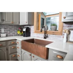 a kitchen with gray cabinets and white counter tops, an old - fashioned copper sink