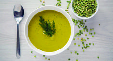 two bowls filled with soup on top of a table next to a spoon and sprinkled seeds