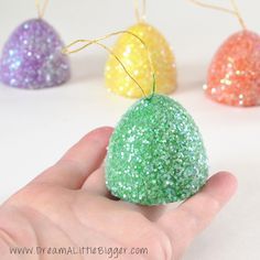 a hand is holding an ornament with glitter on it