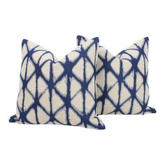 two blue and white pillows on a white background