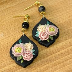 the earrings are decorated with flowers on black and gold earwires, along with beads