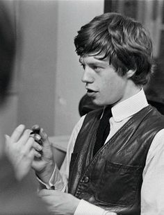 black and white photograph of man in vest looking at cell phone