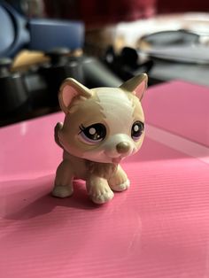 a small toy dog sitting on top of a pink table