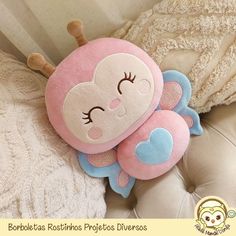 a pink stuffed animal laying on top of a white couch next to a pillow with eyes closed