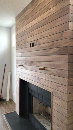 an empty fireplace with wood paneling on the wall and floor in front of it