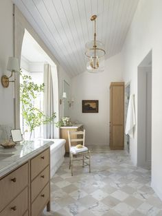 a large bathroom with marble flooring and white walls, along with a chandelier hanging from the ceiling