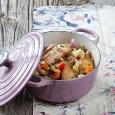 a casserole dish with meat and vegetables in it on a floral tablecloth