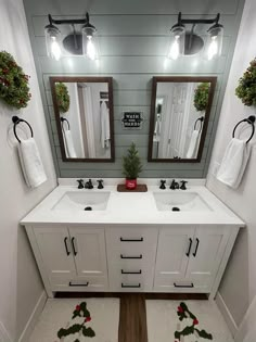 a bathroom with two sinks, mirrors and christmas decorations on the counter top in front of it