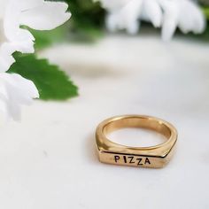 "This is a perfect Christmas gift for your favorite person! This is a fun and flirty band ring hand stamped with \"PIZZA\" in cute uppercase font. It has a flat top which gives it a 90s vibes. This ring is great to wear alone or stack in multiples. All rings come beautifully and simply packaged in an eco-friendly kraft box and twine ready for gifting. About the jewelry: * This stainless steel band ring is plated with gold. * For custom text (up to 7 characters or fewer), please add at checkout. Trendy Personalized Rings For Everyday, Trendy Personalized Everyday Rings, Trendy Adjustable Stackable Rings For Anniversary, Trendy Stackable Rings For Anniversary, Trendy Personalized Rings For Promise, Trendy Stackable Midi Rings For Anniversary, Trendy Personalized Promise Ring, Trendy Personalized Adjustable Rings, Pizza Jewelry