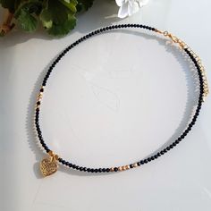 3mm black Tourmaline choker and matte gold Bohemian glass beads with an old gold heart pendant. MEASURES 35, 40, 45, 50, 55 and 60 cm. + 5cm extender.  There is the possibility of removing the extender in case you do not want it. Contact me to detail your request  💎M A T E R I A L S - Black Tourmaline beads 3mm.   The stones are natural so they will never be the same as each other. - 3mm gold Bohemian glass beads. - Old gold heart pendant. - Stainless steel closures. - Unbreakable steel thread for linking beads. 📦PACKAGING Very nice packaging ready to give away if desired. - Navy blue box with the logo (measured according to the size of the jewel). - Light brown natural linen burlap bag, VIP card with 15% discount,    wipe to clean the jewel and some delicious sweets. - Padded bag for pr Adjustable Gold Beaded Necklace With Heart Charm, Elegant Black Heart Pendant Choker, Elegant Gold Choker With Heart Charm, Black Heart Pendant Choker With Charm, Black Heart Pendant Choker With Heart Charm, Black And Gold Necklace, Black Tourmaline Necklace, Elegant Choker, Vip Card