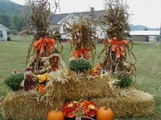 hay bales with pumpkins and flowers on them in front of a large house