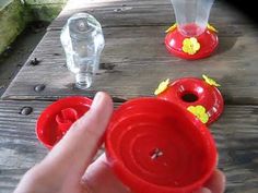 a hand holding a red plastic cup with yellow flowers on it and two empty water bottles in the background