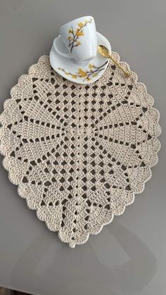 a crocheted doily with a cup and saucer on it