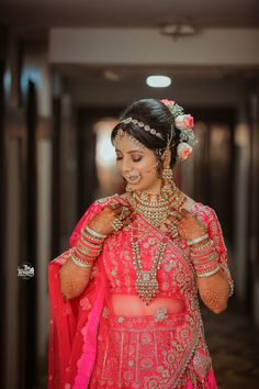 a woman in a red and gold bridal outfit is smiling at the camera while wearing jewelry