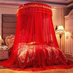 a bed with a red canopy over it in a room next to a lamp and dresser