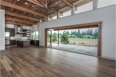 an empty kitchen and living room in a house with wood flooring, large sliding glass doors to the outside