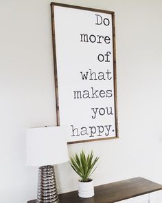 a sign that says do more of what makes you happy next to a lamp on a table