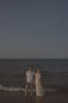 a man and woman standing in the water at the beach