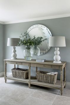 a table with two lamps and a mirror on the wall above it, in a living room