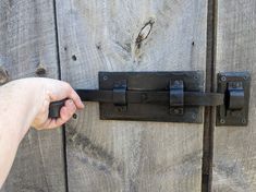 a hand is holding the handle on a wooden door