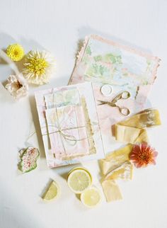 some lemons, scissors and other items are on a white surface with flowers in the background