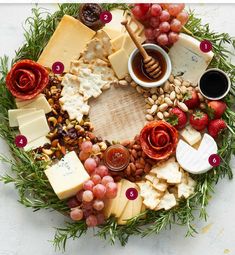 a cheese platter with grapes, nuts, and other food items arranged in the shape of a circle