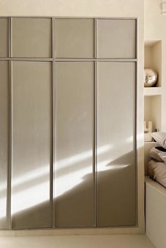 an empty bedroom with white walls and beige bedding is pictured in this image, there are shelves on either side of the closet