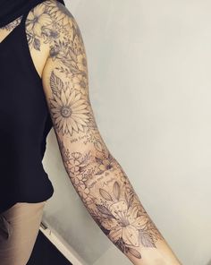 a woman's arm with flowers and butterflies tattooed on the back of her arm