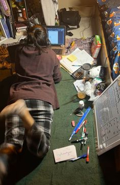 a woman is sitting on the floor with her laptop and many other items around her