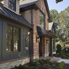 a brick house with large windows and lots of greenery