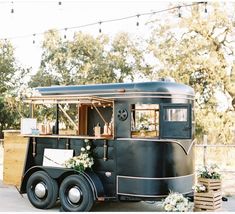 an old fashioned food truck is decorated with flowers and greenery for a wedding reception