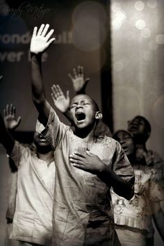 a group of young people standing next to each other holding hands up in the air