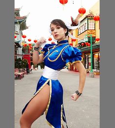 a woman in a blue and white outfit is posing for a photo on the street