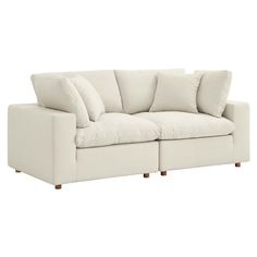 a white couch with four pillows on it's back and one arm facing the camera