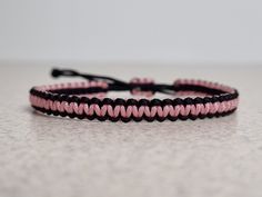 a pink and black string bracelet on a table