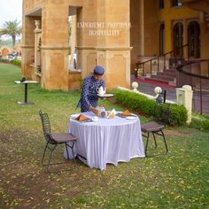 a man standing at a table with food on it in front of an old building