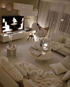 a living room filled with lots of white furniture and lights on top of the walls