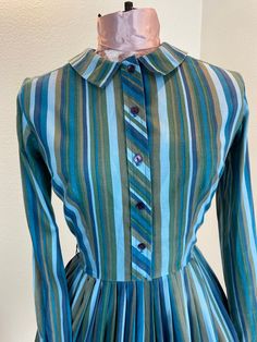 "1960's Blue And Green Stripe Shirt Dress This is such a great shirt dress. The stripes and the careful placement of them make this shirt dress next level attractive. Just check out the pictures and see how the stripes were perfectly utilized to make a regular cut shirt dress into something special. This dress is a button front closure, has her makers tag, which is frayed. Maker is Carol Rodgers Juniors Measurements provided are flat and have been doubled. Bust 34\" Waist 25\" Hips free\" Length Fitted Striped Long Sleeve Shirt Dress, Striped Fitted Cotton Shirt Dress, Fitted Striped Cotton Shirt Dress, Striped Cotton Shirt Dress With Buttons, Fitted Striped Shirt Dress For Daywear, Retro Blue Button-up Dress, Striped Fitted Collared Dress, Fitted Striped Collared Dress, Fitted Striped Shirt Dress With Buttons