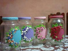 four glass jars are decorated with flowers and hearts