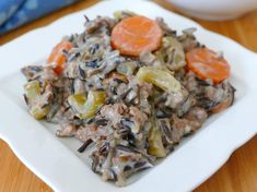 a white plate topped with rice and carrots on top of a wooden table next to a bowl