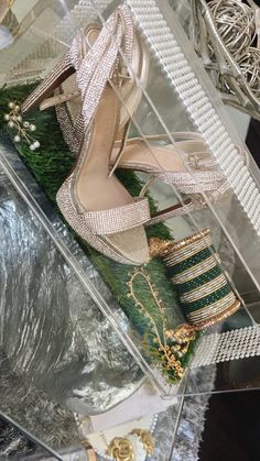 a pair of high heeled shoes sitting on top of a glass box filled with jewelry